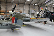 Supermarine Spitfire, Curtiss P-47 G 'Thunderbolt', Grumman F8F-2P 'Bearcat' und North American P-51 'Mustang' dicht gedrängt im Hangar des IWM stehend 
